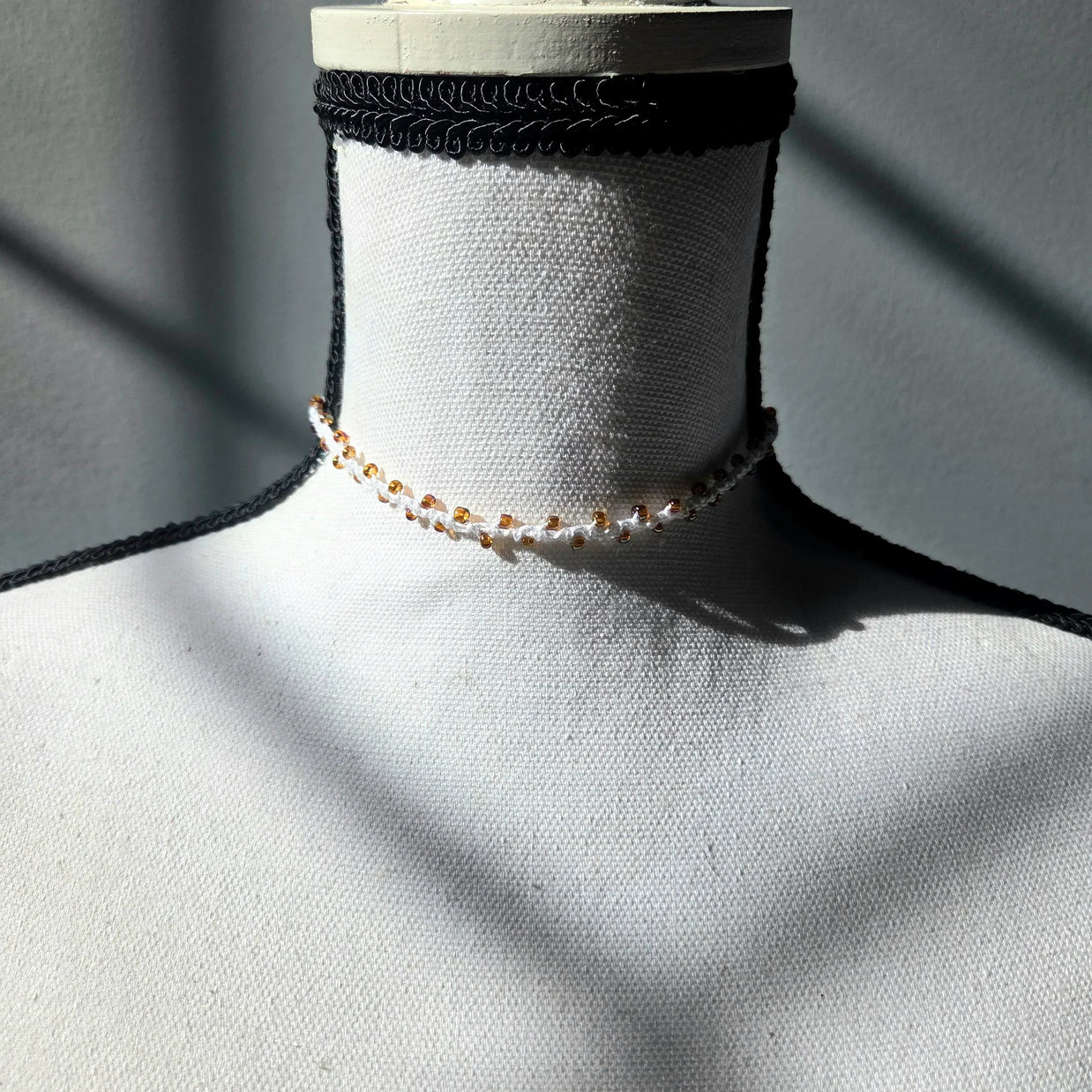 Handmade crochet choker necklace with amber beads, displayed on mannequin neck for cozy, creative style.