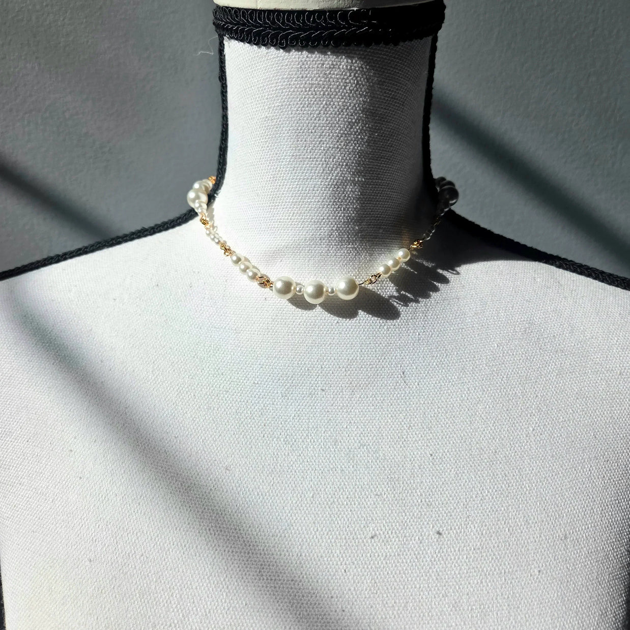 Delicate pearl necklace with gold chain on white mannequin, elegant handmade jewelry for everyday wear