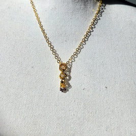 Gold chain necklace with interlocking rings and small beads, displayed on white fabric background