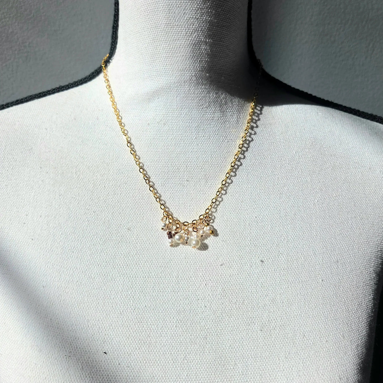 Delicate gold chain necklace with pearl and bead cluster pendant, perfect for cozy everyday wear.