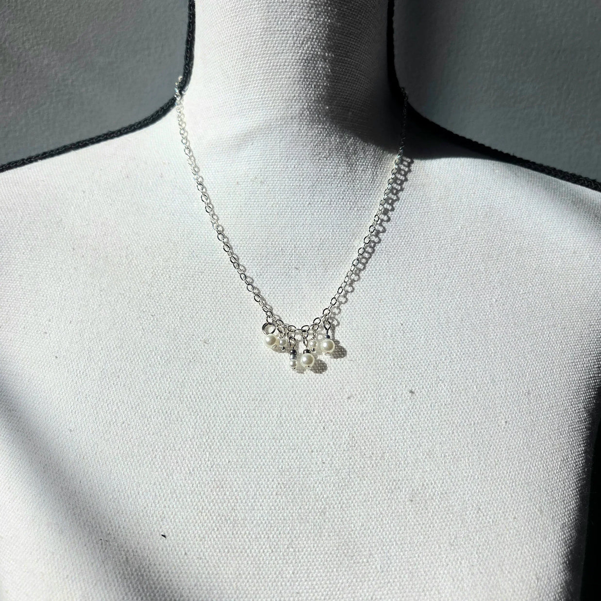 Delicate silver necklace with pearl charms on a white display bust, perfect for everyday elegance.