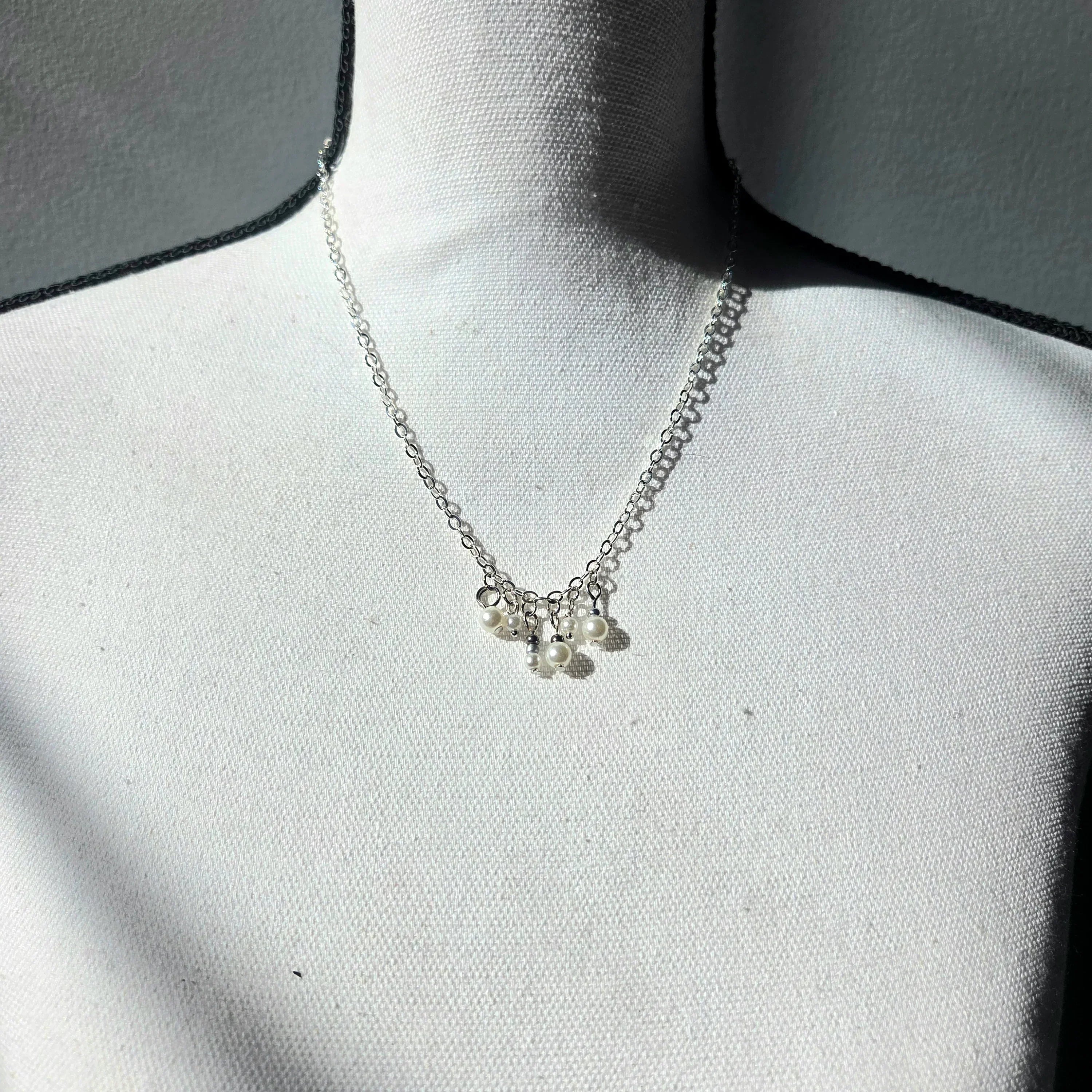 Delicate silver necklace with pearl charms on a white display bust, perfect for everyday elegance.