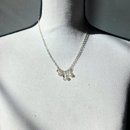 Delicate silver necklace with pearl charms on a white display bust, perfect for everyday elegance.