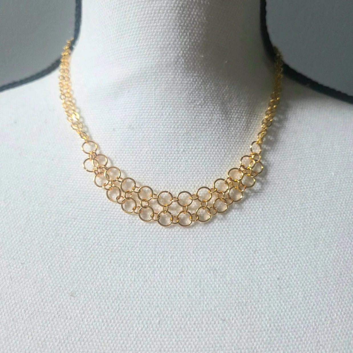 Gold chainmaille necklace with interlocking rings, displayed on white bust for handmade jewelry gift