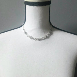 Delicate silver chainmaille necklace with floral links, displayed on a mannequin for handmade jewelry lovers.