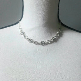 Silver chainmaille necklace with floral links on white display bust