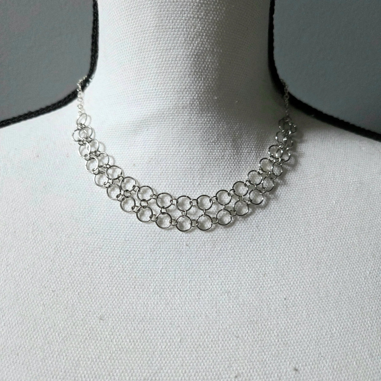 Silver chainmaille necklace with interlocking rings, displayed on a white fabric bust for elegant everyday wear.