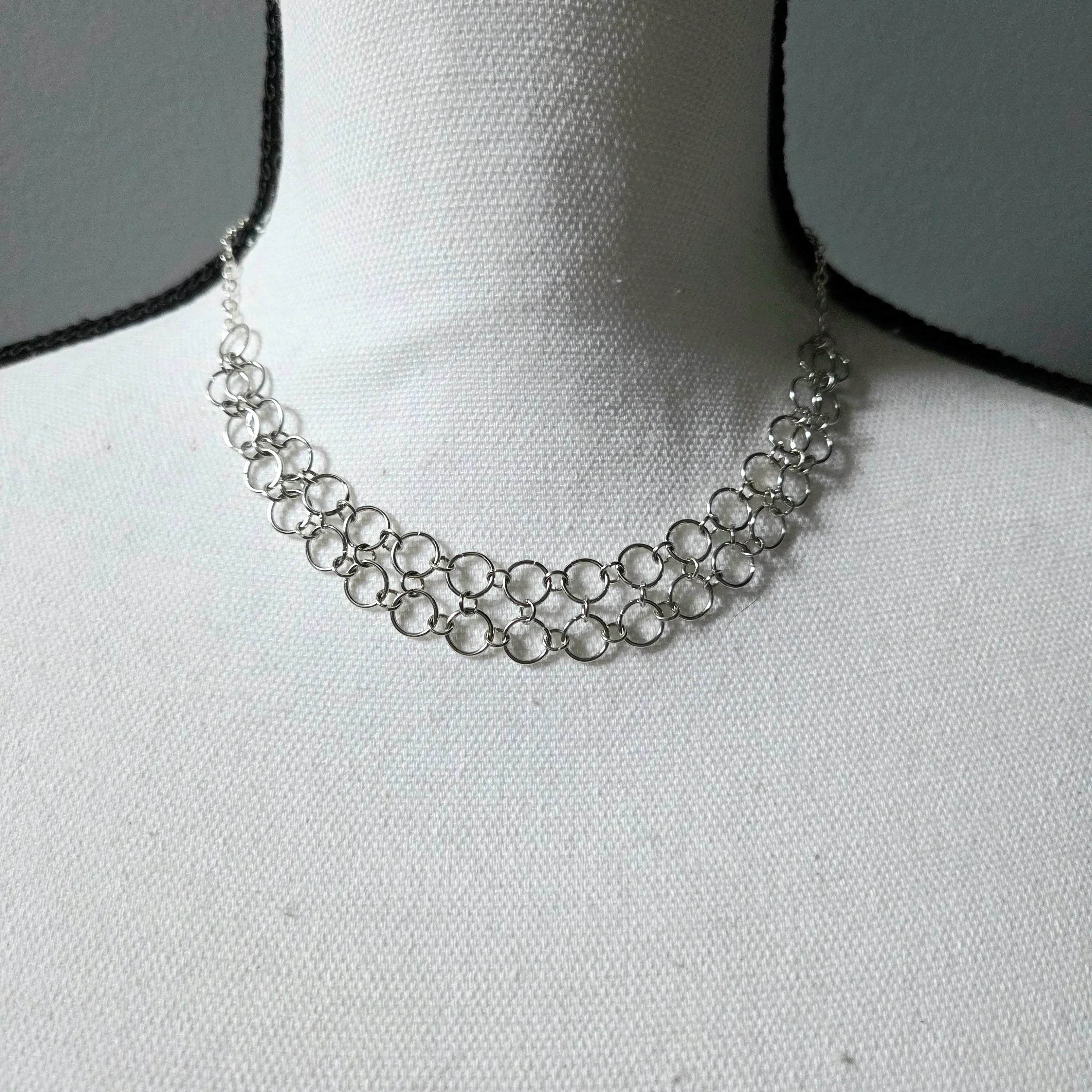 Silver chainmaille necklace with interlocking rings, displayed on a white fabric bust for elegant everyday wear.