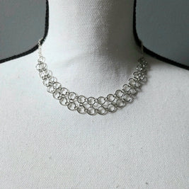 Silver chainmaille necklace with interlocking rings, displayed on a white fabric bust for elegant everyday wear.