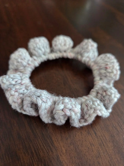 Handmade crochet scrunchie with bobble edge on a dark wood table