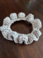 Handmade crochet scrunchie with bobble edge on a dark wood table