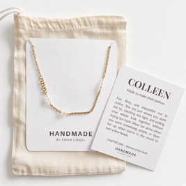 A delicate gold chain necklace is displayed on a white card next to a beige fabric drawstring bag and a printed insert card reading 'COLLEEN' by Handmade by Erika Liesel, arranged on a light neutral background.
