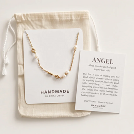 A gold and white pearl necklace displayed on a white card, with a cream drawstring pouch and a printed card titled 'ANGEL' by Handmade by Erika Liesel on a light neutral background.