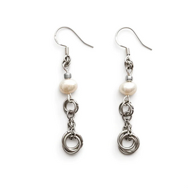 A pair of silver-toned dangle earrings with a single irregular white freshwater pearl and three interlinked silver rings, shown on a plain white background.