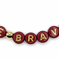 Handmade by Erika Liesel Be Brave stretch bracelet featuring maroon crystal beads and gold-plated accent beads.