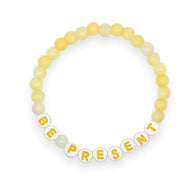 Handmade by Erika Liesel Be Present bracelet with soft yellow glass beads and white letter beads on elastic cord.