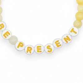 Handmade by Erika Liesel Be Present stretch bracelet with soft yellow glass beads and white letter beads