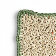 Handmade by Erika Liesel beige crocheted cotton placemat with a green border and subtle multi-colored yarn flecks.