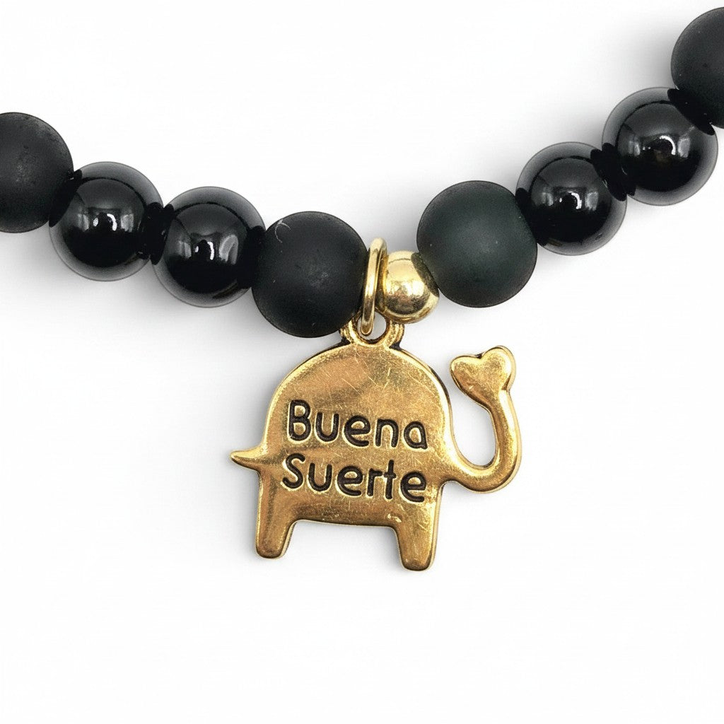 Handmade by Erika Liesel stretch bracelet featuring matte and glossy black glass beads with a gold elephant charm.