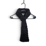 Handmade by Erika Liesel black crochet keyhole scarf hanging on a black hanger against a white background