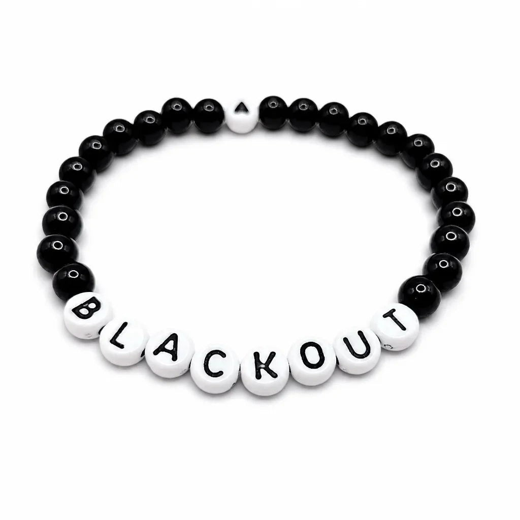 Handmade by Erika Liesel Blackout stretch bracelet with black glass beads and white letter beads on elastic cord.