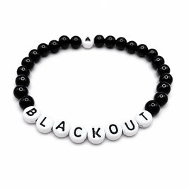 Handmade by Erika Liesel Blackout stretch bracelet with black glass beads and white letter beads on elastic cord.