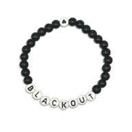 Handmade by Erika Liesel Blackout stretch bracelet with 6mm black glass beads and white letter beads on elastic cord.