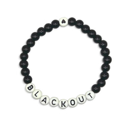 Handmade by Erika Liesel Blackout stretch bracelet with 6mm black glass beads and white letter beads on elastic cord.