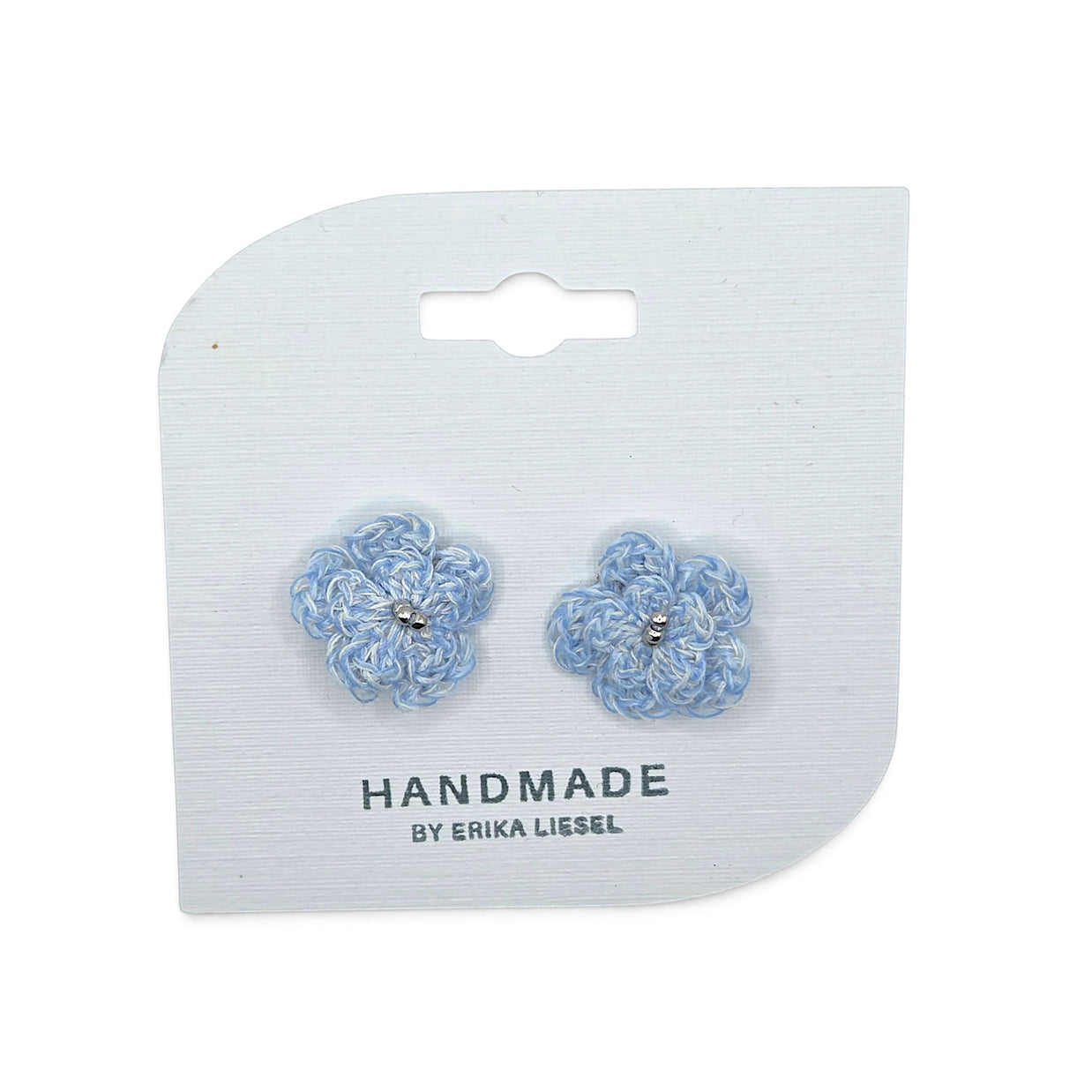 Handmade by Erika Liesel Bloom crochet flower earrings in light blue with silver bead accents on a display card.