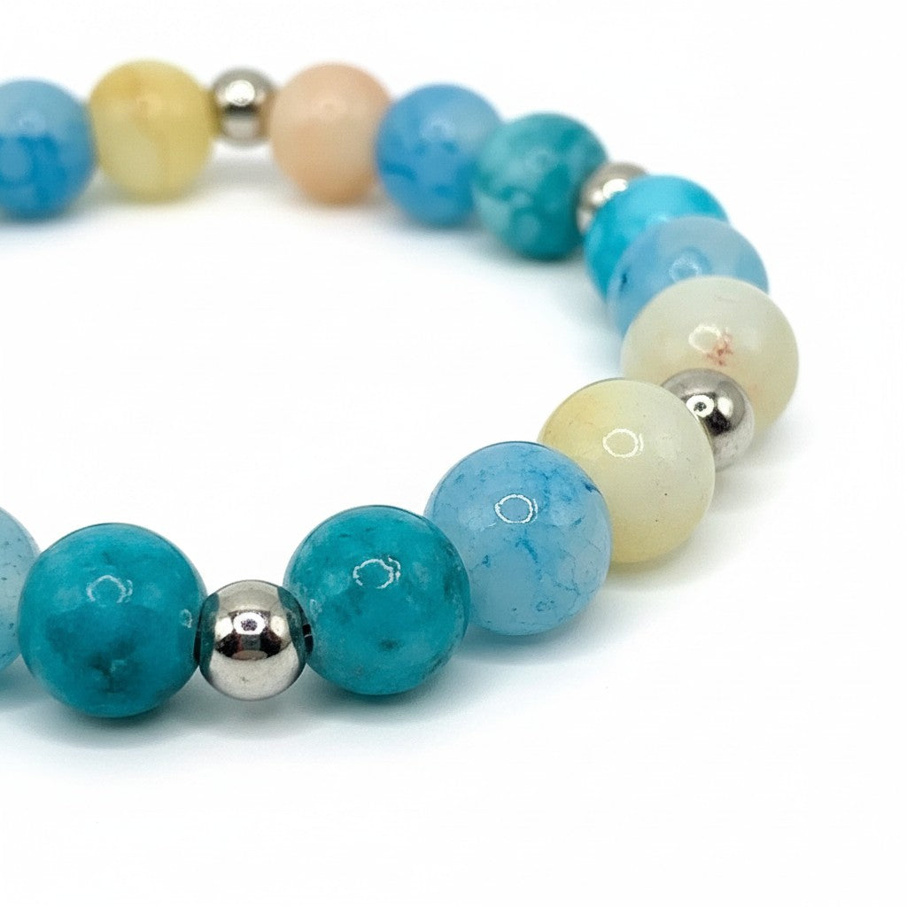Handmade by Erika Liesel Blue Lagoon stretch bracelet with aqua, blue, cream, and silver glass beads on white background