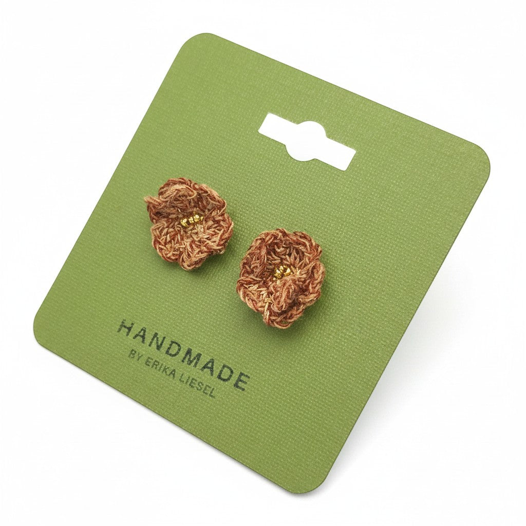 Handmade by Erika Liesel brown crochet flower stud earrings with gold bead centers on a green display card.