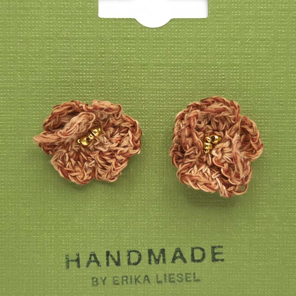 Handmade by Erika Liesel brown crochet flower stud earrings with gold bead centers on a green display card.