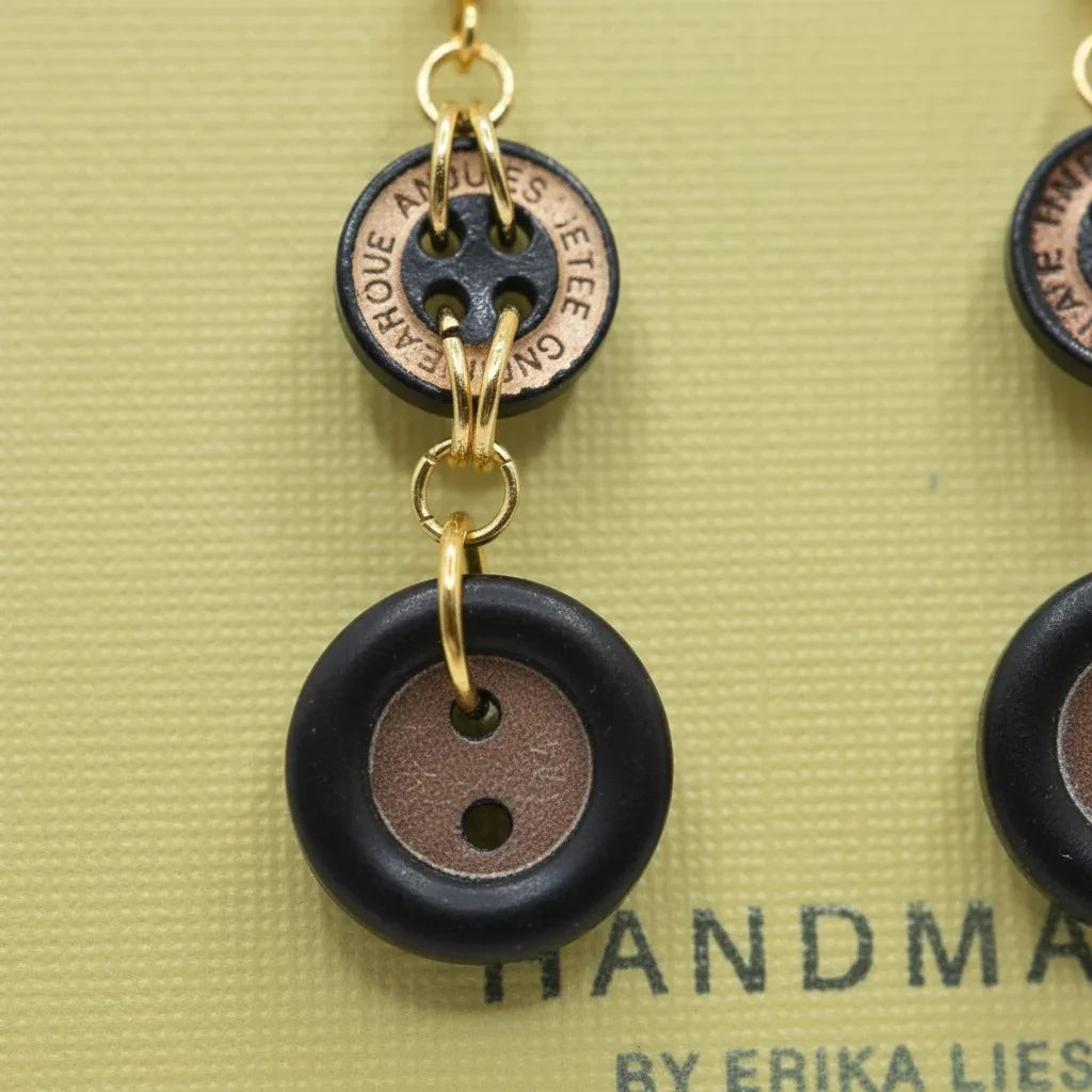 Handmade by Erika Liesel earrings featuring black and copper vintage button charms linked with gold-tone metal rings.