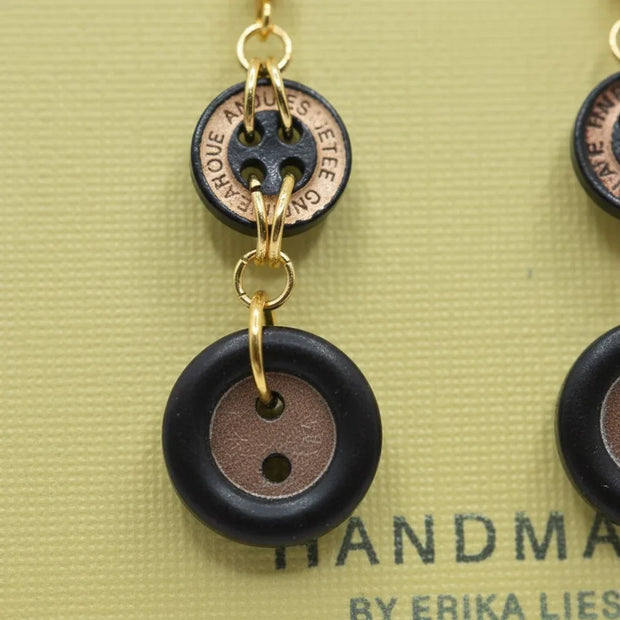 Handmade by Erika Liesel earrings featuring black and copper vintage button charms linked with gold-tone metal rings.