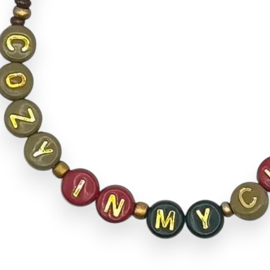 Handmade by Erika Liesel Cozy In My Chaos stretch bracelet with 4mm glass beads and gold-foil letter beads.