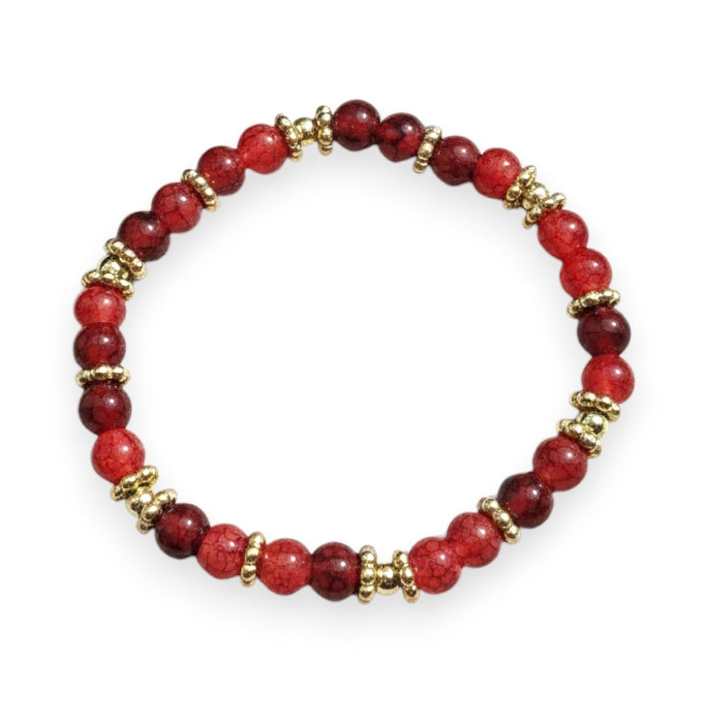 Handmade by Erika Liesel Crimson Charm Bracelet featuring ruby glass beads and gold spacers on a rustic wood surface.