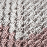 Close-up of a Handmade by Erika Liesel crochet bandana featuring soft beige and dusty rose yarn in a textured pattern.