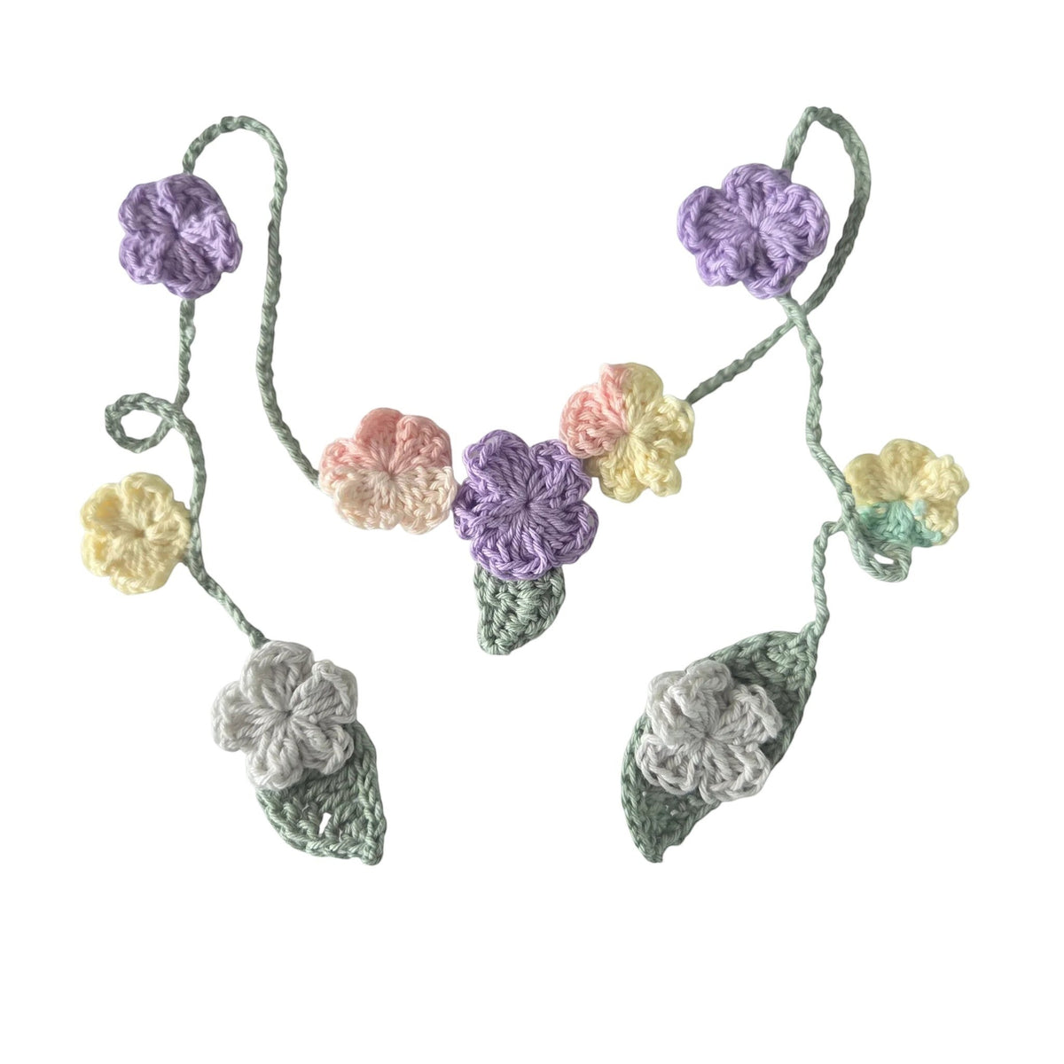Handmade by Erika Liesel crochet floral garland featuring pastel flowers and green leaves on a soft yarn string