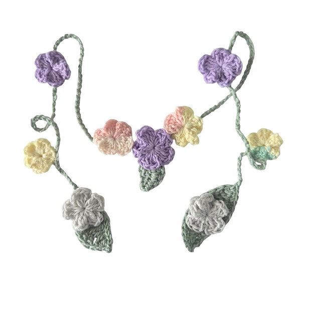 Handmade by Erika Liesel crochet floral garland featuring pastel flowers and green leaves on a soft yarn string