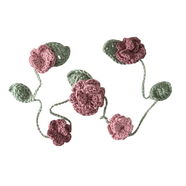Handmade by Erika Liesel crochet floral garland featuring dusty pink flowers and sage green leaves on a string.