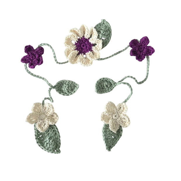 Handmade by Erika Liesel crochet floral garland with purple and cream flowers and sage green leaves on a vine.