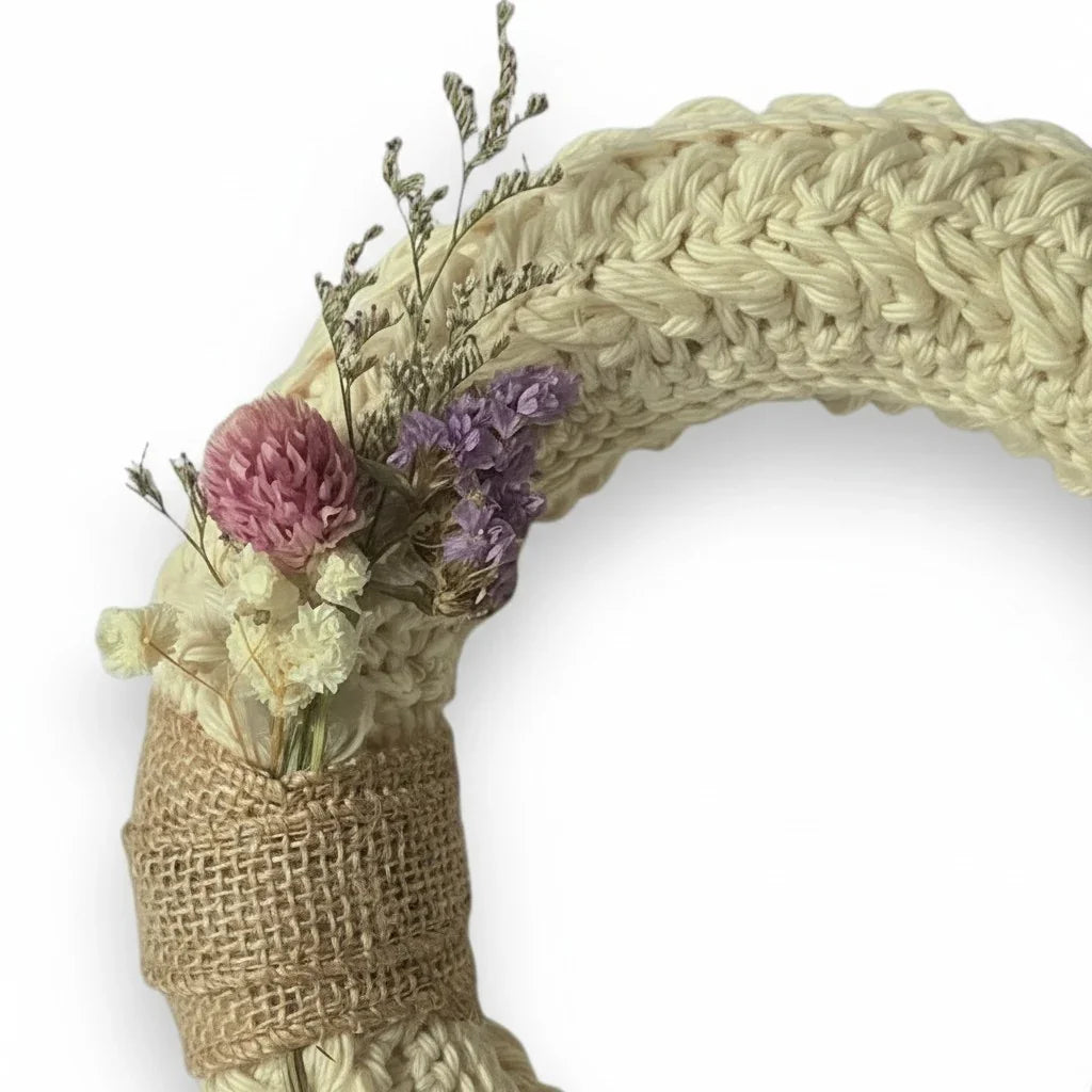 Handmade by Erika Liesel small crochet wreath in cream yarn with dried pink and purple floral accents and burlap trim