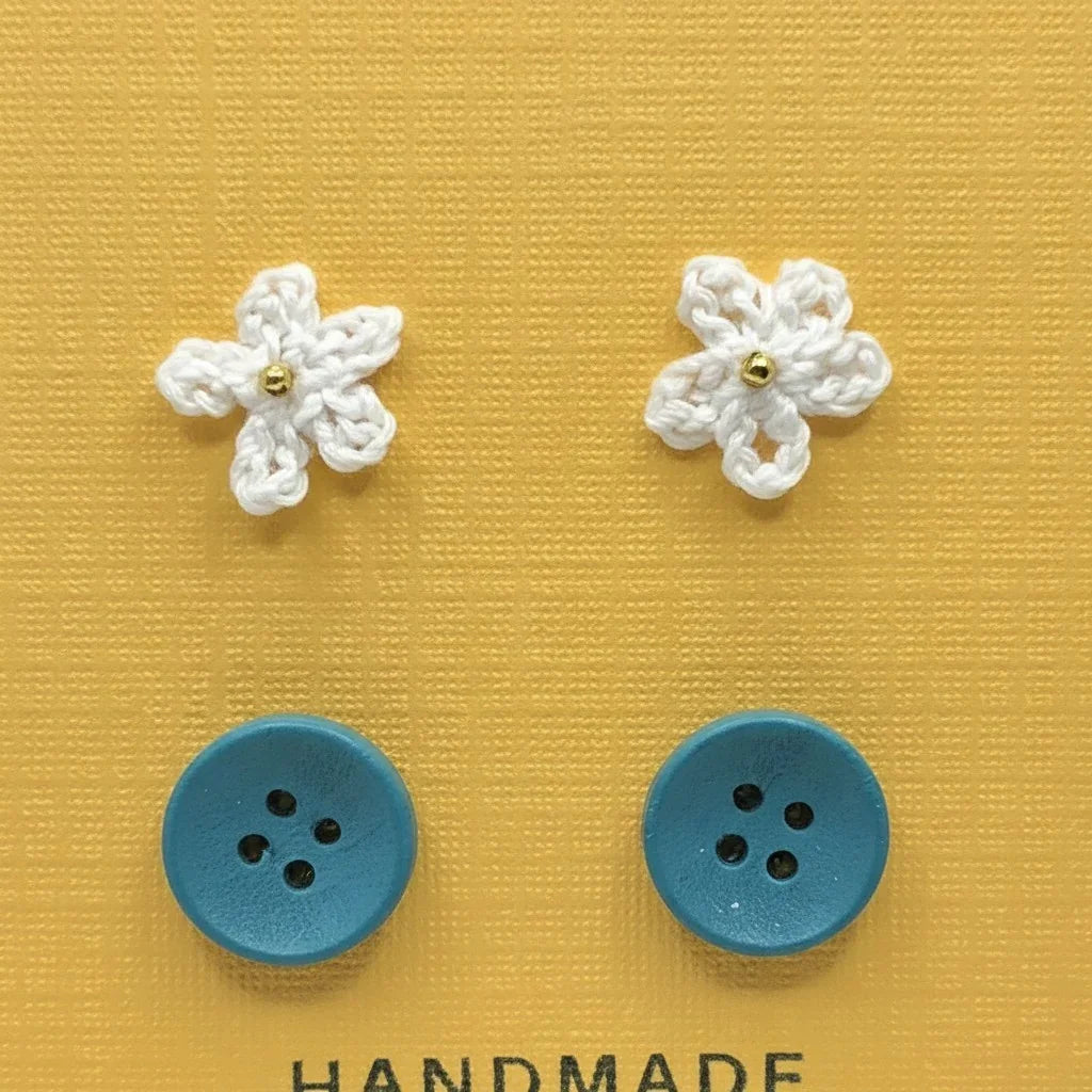 Handmade by Erika Liesel Cute-As-A-Button set featuring white crocheted flower studs and blue button stud earrings.