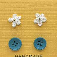 Handmade by Erika Liesel Cute-As-A-Button set featuring white crocheted flower studs and blue button stud earrings.