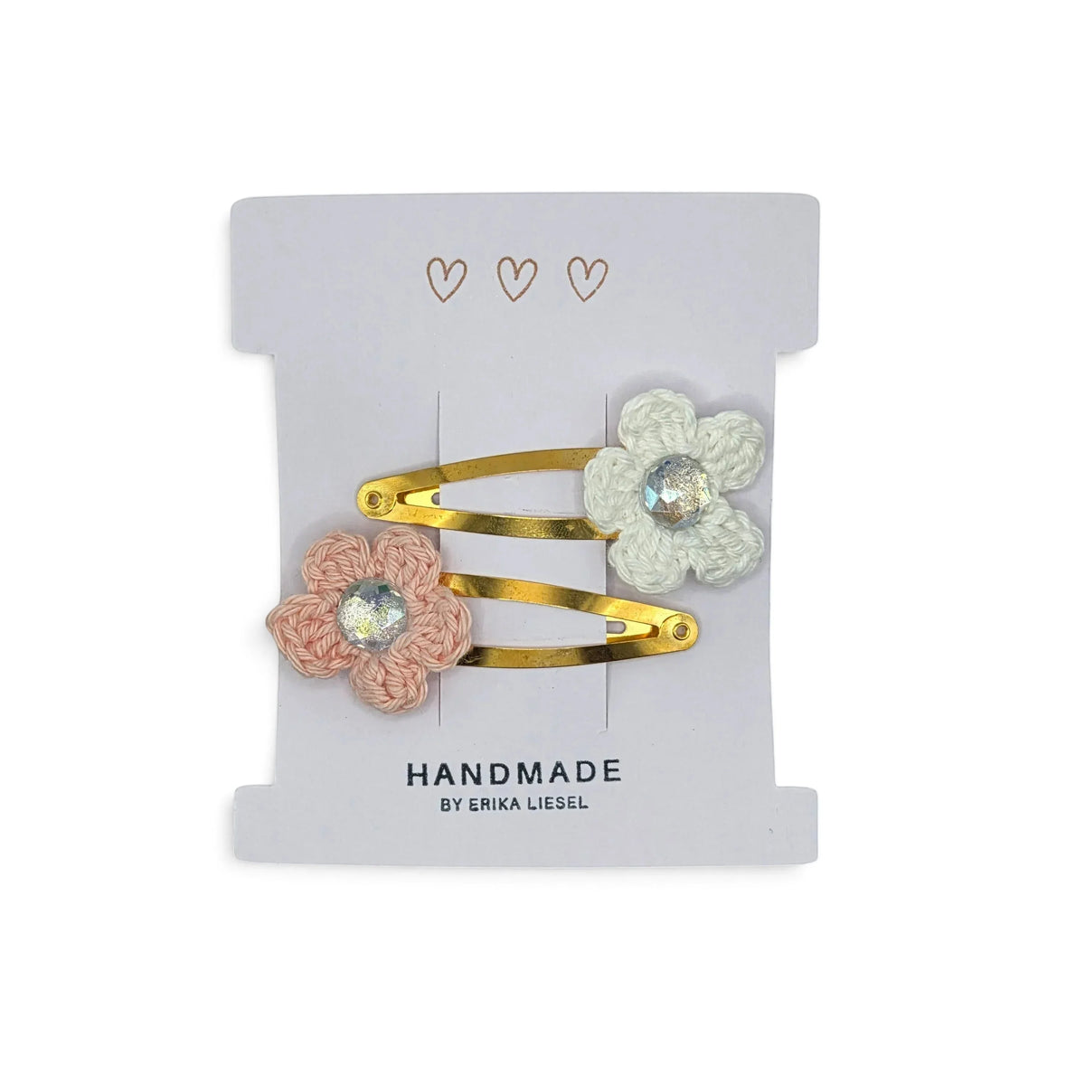 Handmade by Erika Liesel crochet flower snap clips in pink and white with rhinestone centers on a display card.
