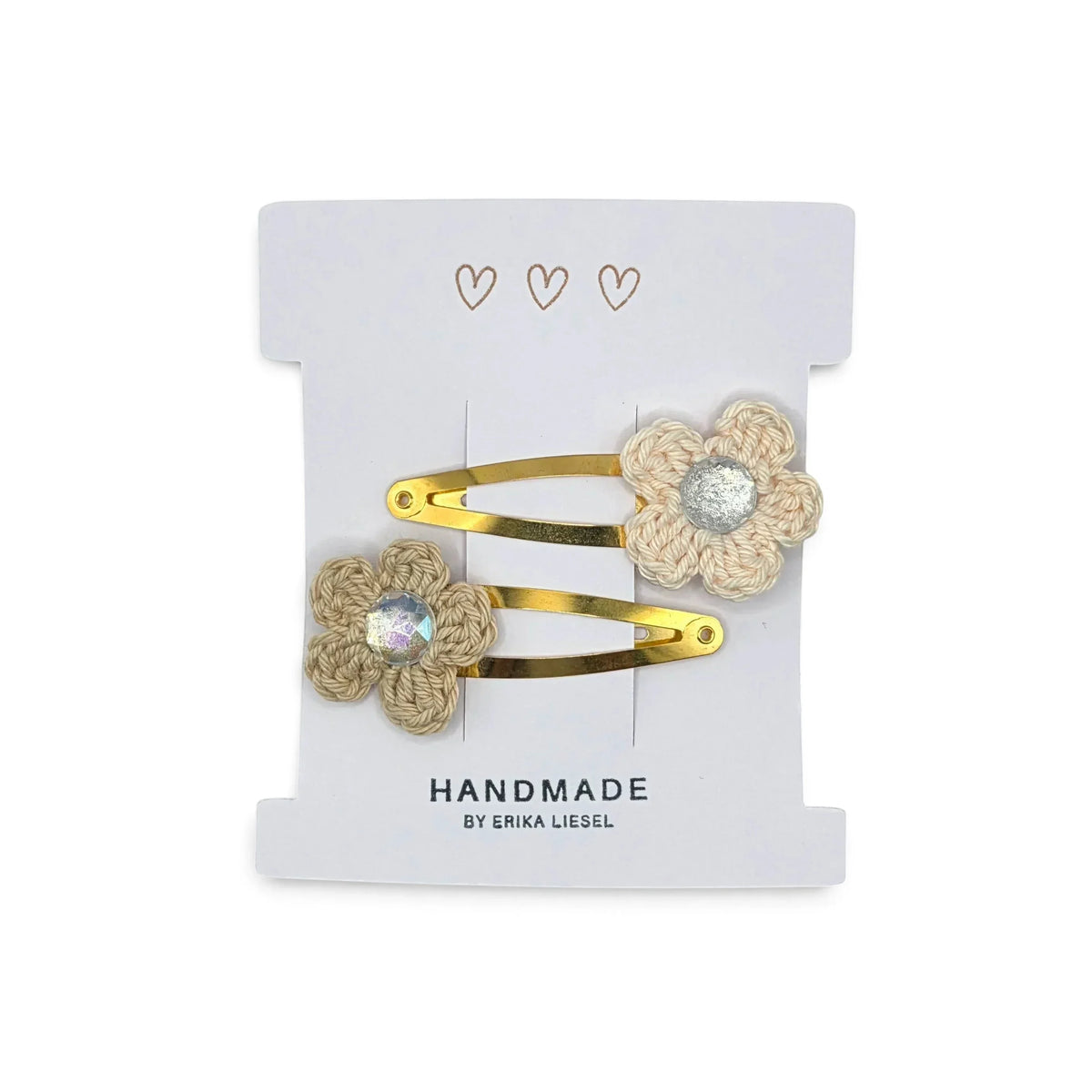 Handmade by Erika Liesel crochet flower snap clips in cream with sparkling rhinestone centers on a display card.