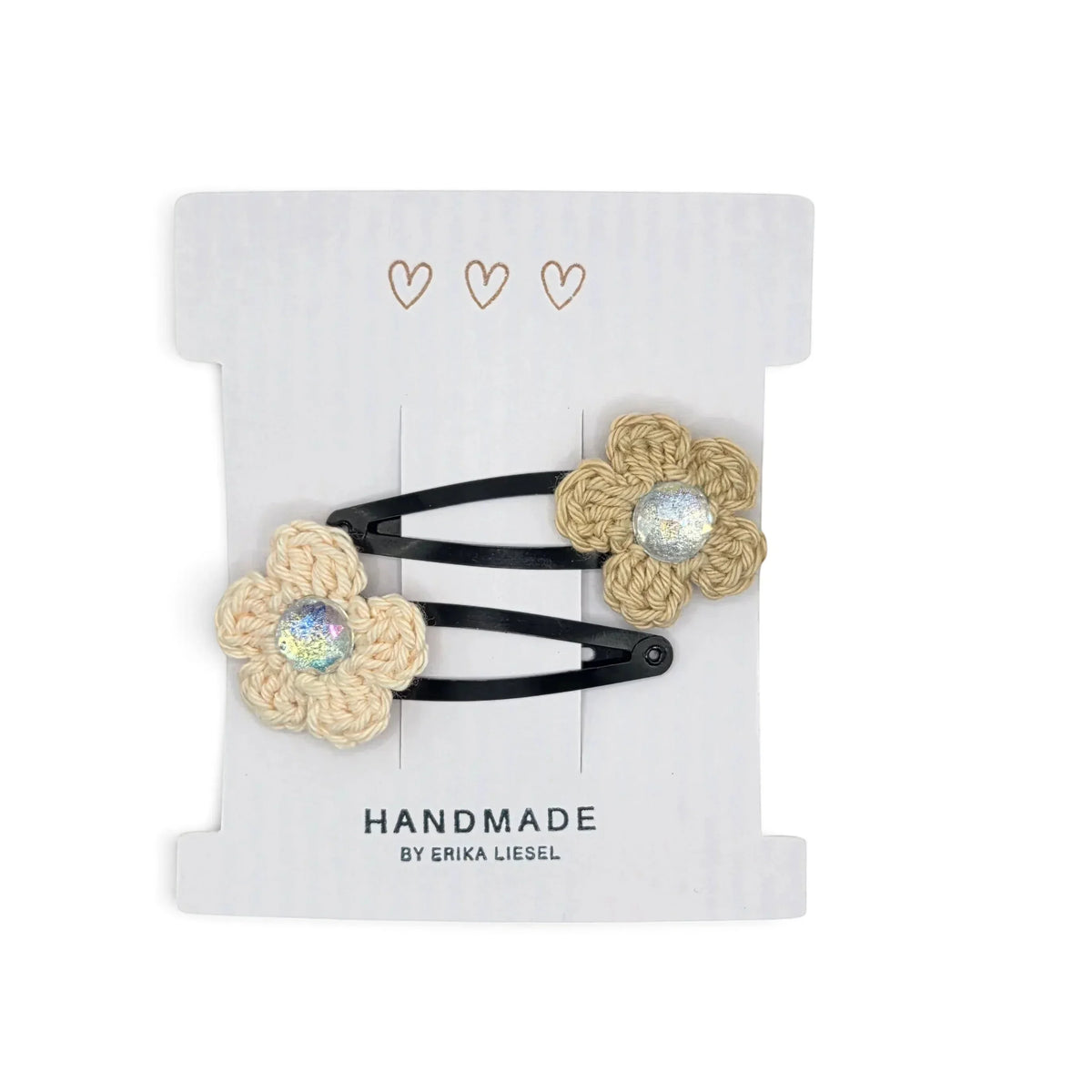Handmade by Erika Liesel crochet flower snap clips in beige with sparkling rhinestone centers on a display card.