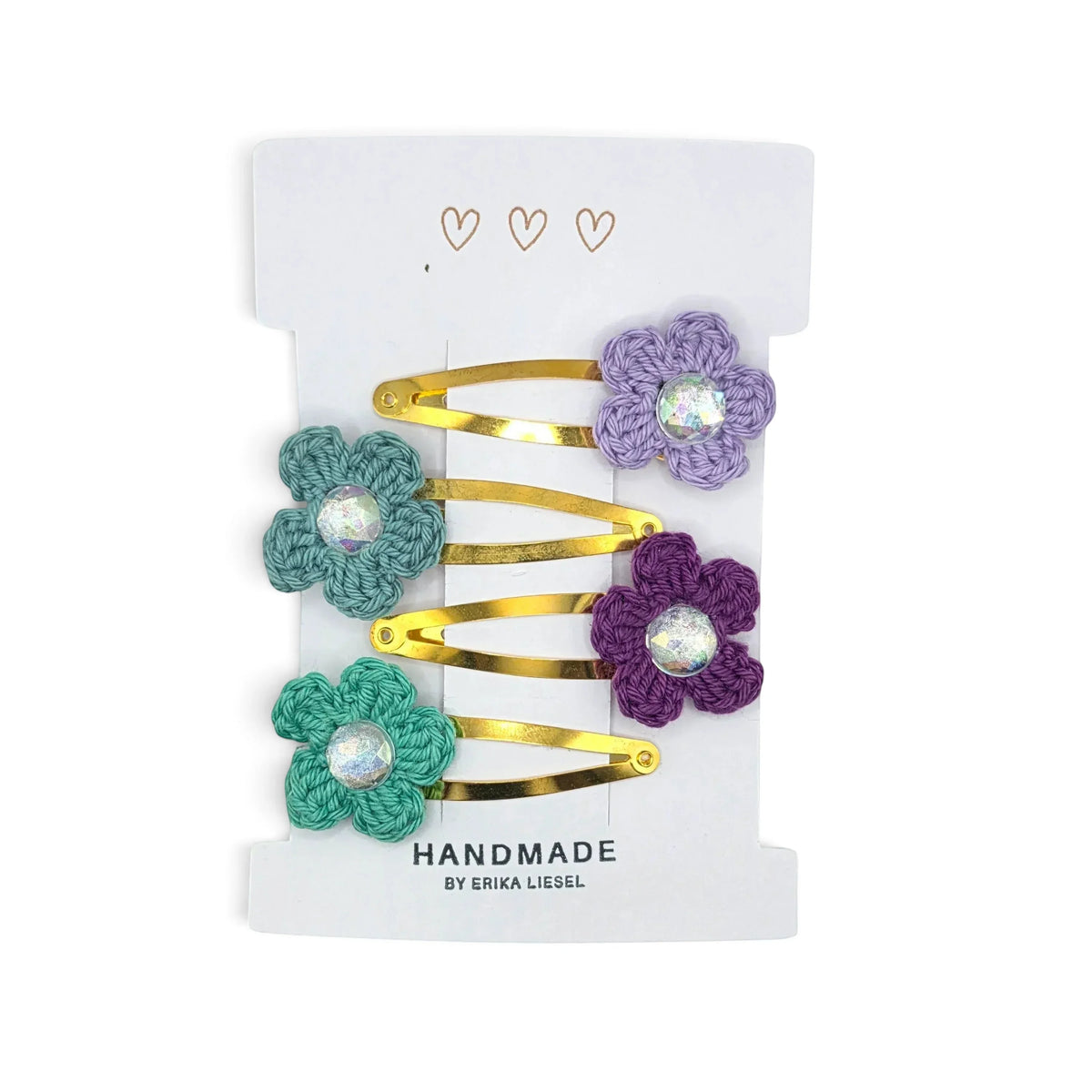Handmade by Erika Liesel crochet flower snap clips in purple, teal, and dark purple with sparkling rhinestone centers.