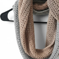 Handmade by Erika Liesel crochet infinity scarf in grey and tan acrylic blend yarn hanging on a black hanger
