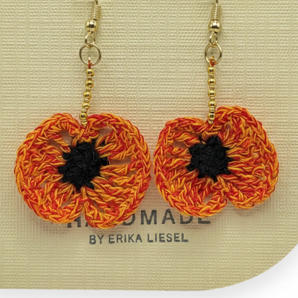 Handmade by Erika Liesel orange and black crochet poppy flower earrings with gold bead accents and gold hooks.